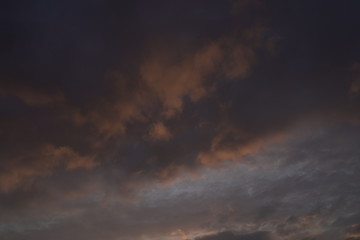 Beautiful evening blue sky at sunset with flaming bright light clouds. A warm summer evening at sunset.