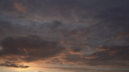 Obraz premium Beautiful evening blue sky at sunset with flaming bright light clouds. A warm summer evening at sunset.