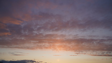 Beautiful evening blue sky at sunset with flaming bright light clouds. A warm summer evening at sunset.