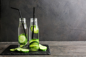 Bottles of infused cucumber water on dark background