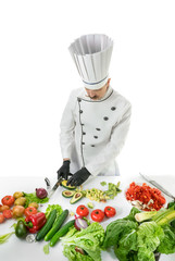 Chef cook cuts the avocado with a knife at the white table with a vegetables