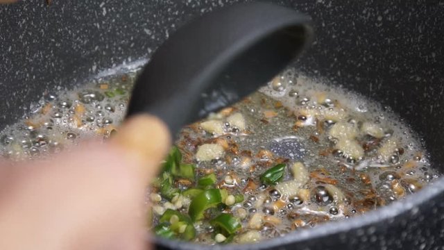 Frying Onions with green chilies, garlic, ginger and cumin seeds to make Tadka to make of spicy Indian lentils called Daal tadka. A 4K video resolution.