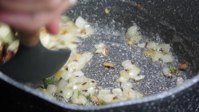 Frying Onions with green chilies, garlic, ginger and cumin seeds to make Tadka to make of spicy Indian lentils called Daal tadka. A 4K video resolution.