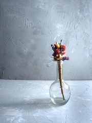 decorative bottle with dry flowers on a gray background