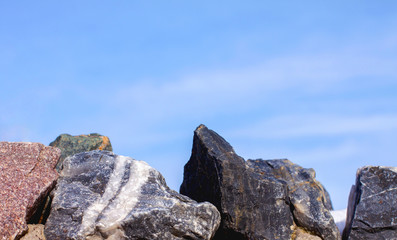 Large stones close-up at the bottom of the frame against a blue cloudy sky