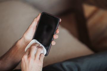 Corona virus protection, closeup disinfecting surfaces with disinfectant, stay home and safe, avoid contamination with covid 19, phone disinfecting