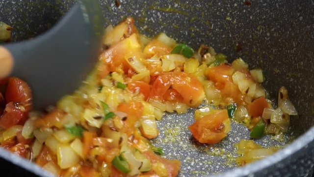 Frying Onions with green chilies, garlic, ginger and cumin seeds to make Tadka to make of spicy Indian lentils called Daal tadka. A 4K video resolution.