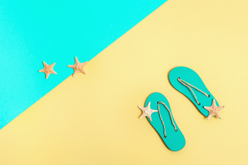 Concept of beach holiday. Beach flip-flops and small starfishes on bright paper background. Summer...