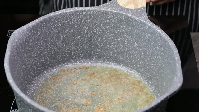 Cumin seeds spluttering and cooking in Desi Ghee or clarified butter. The making of spicy Indian lentils called Daal tadka. A video in 4K resolution.