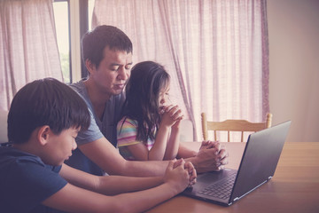 Children praying with father parent with laptop, family and kids worship online together at home,...