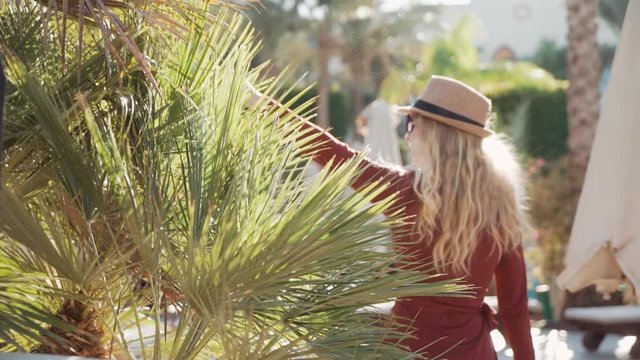 A lady is playing with pulm tree with her fingers and walking away
