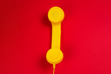 Yellow handset on red background.