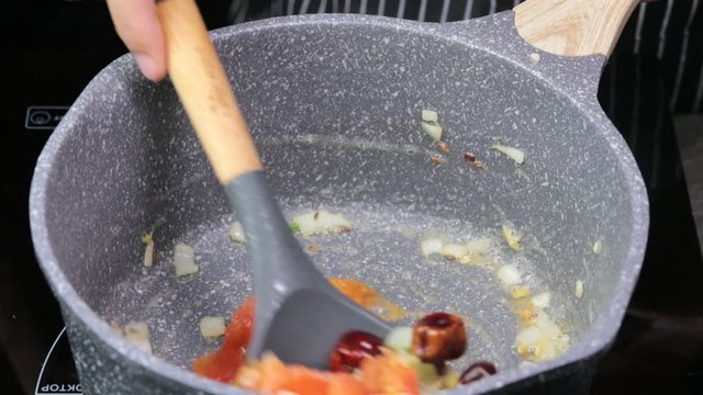 Frying Onions with green chilies, garlic, ginger and cumin seeds to make Tadka to make of spicy Indian lentils called Daal tadka. A 4K video resolution.