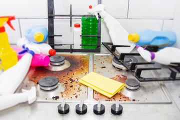 dirty kitchen stove, empty and full bottles of detergents around.