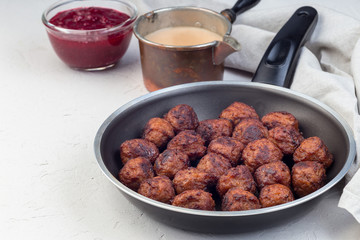 Meatballs served with cream sauce and cranberry jam,  in iron pan, horizontal