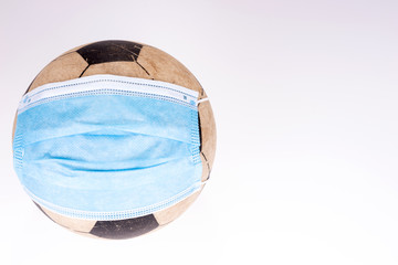 Soccer ball wearing a protective mask. Concept of sports suffering from the COVID-19 pandemic