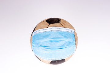 Soccer ball wearing a protective mask. Concept of sports suffering from the COVID-19 pandemic