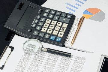 Business financial documents, office calculator and pen on the table. Numbers and graphs