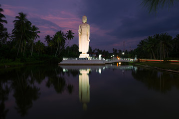 Sculpture of a standing Buddha in the evening twilight. Hikkaduwa, Sri Lanka