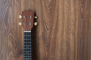 Brown ukulele guitar portrait on texture Wall plaster ,Vintage dark tone holiday relax break time with music or art concept with copy space for your text