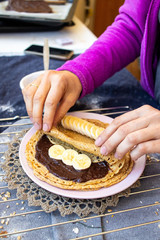 Crepes with chocolate and bananas or thin pancakes. Vegan food sweet breakfast. Woman hands
