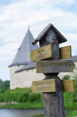 Road sign with inscriptions in Russian on the background of the tower and walls of the fortress (Staraya Ladoga, Russia)