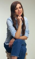 Portrait of smiling young woman in blue shirt sitting with crossed arms.