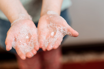 Children's hands in soapy foam.