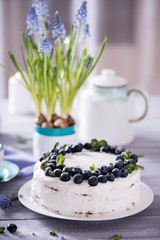 Fototapeta na wymiar A beautiful and tasty cake with white cream and fresh blueberries decorated with mint leaves. Sweet tasty cheesecake, berry pie.