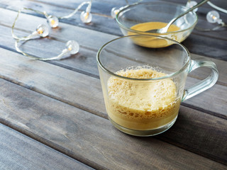transparent mug with coffee on a wooden background with a garland
