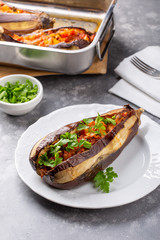 Whole eggplant stuffed with vegetables on white plate on grey background . Imam bayildi, Turkish cuisine.