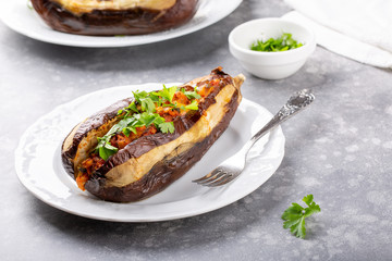 Whole eggplant stuffed with vegetables on white plate on grey background . Imam bayildi, Turkish cuisine.