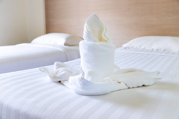 White towel folded into flower and candle shape on bed in hotel resort room to welcome guest