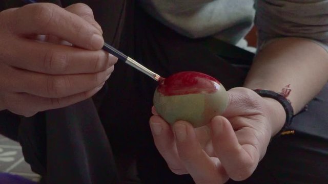 Close up slow motion of caucasian woman, painting an egg with a brush  for easter