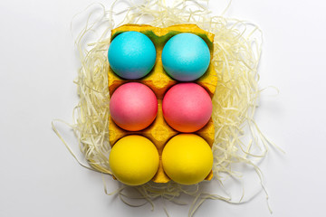 Colorful Easter eggs in yellow paper egg tray isolated on white background. Close-up, top view, design idea