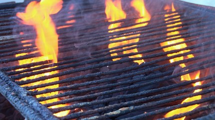 Barbacoa de carbón encendida con llamas y brasas preparándose para poder asar la comida.