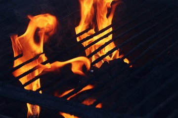 Barbacoa de carbón encendida con llamas y brasas preparándose para poder asar la comida.