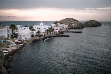 Fototapeta na wymiar La Isleta del Moro, a small town by the sea at dawn with boats moored out of the water, typical white houses with undamaged land and palm trees.