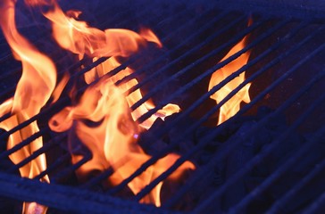 Barbacoa de carbón encendida con llamas y brasas preparándose para poder asar la comida.