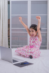 A girl is using a computer in bed to happily study online at home while at home during the period of the outbreak of the covid-19 virus.