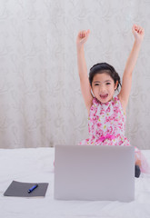 A girl is using a computer in bed to happily study online at home while at home during the period of the outbreak of the covid-19 virus.