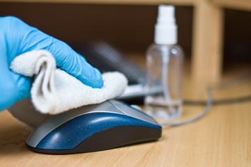 Wipe with antibacterial wipe on the surface of a computer mouse. Coronavirus COVID-19 desktop disinfection