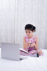 A girl is using a computer in bed to happily study online at home while at home during the period of the outbreak of the covid-19 virus.