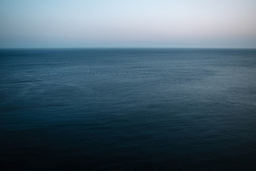 Maritime and minimalist view of the horizon with dark blue sea and cloudless sky.