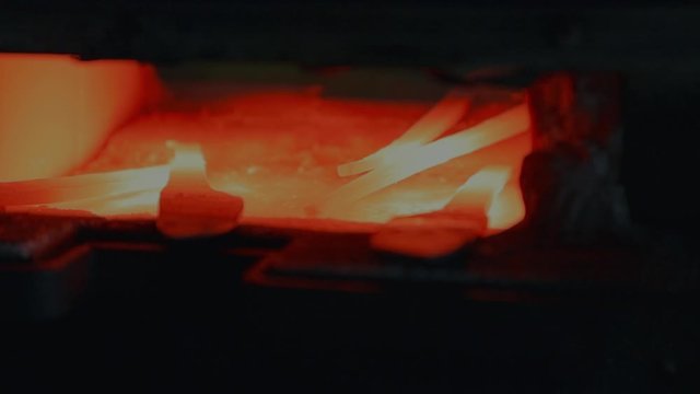 Artistic shot 50mm of hot custom oven for heating steel for a Blacksmith. Custom knives seen in shot being heated to optimum temperature for bending. Slow Motion 120FPS