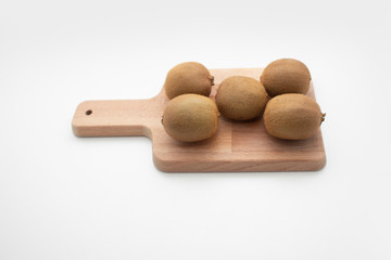 Whole kiwi fruits on chopping board isolated on white background. Organic food or healthy nutrition concept