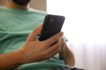 MYKOLAIV, UKRAINE - MARCH 16, 2020: Man holding iPhone 11 Black indoors, closeup