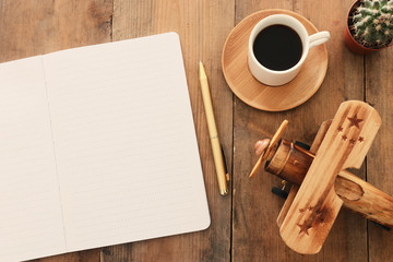 top view image of open notebook with blank pages next to cup of coffee on wooden table. ready for adding text or mockup