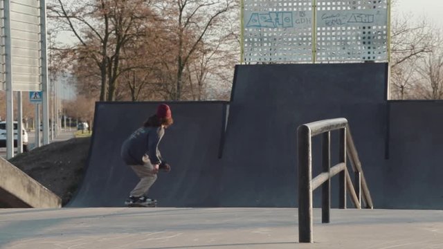 Slowmotion shot of a skateboarder doing a alley-hop Air Indy grab to bank in a skatepark near Barcelona with the sunset light