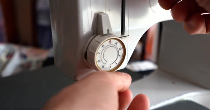 Adding a black thread to a white sewing machine, close up